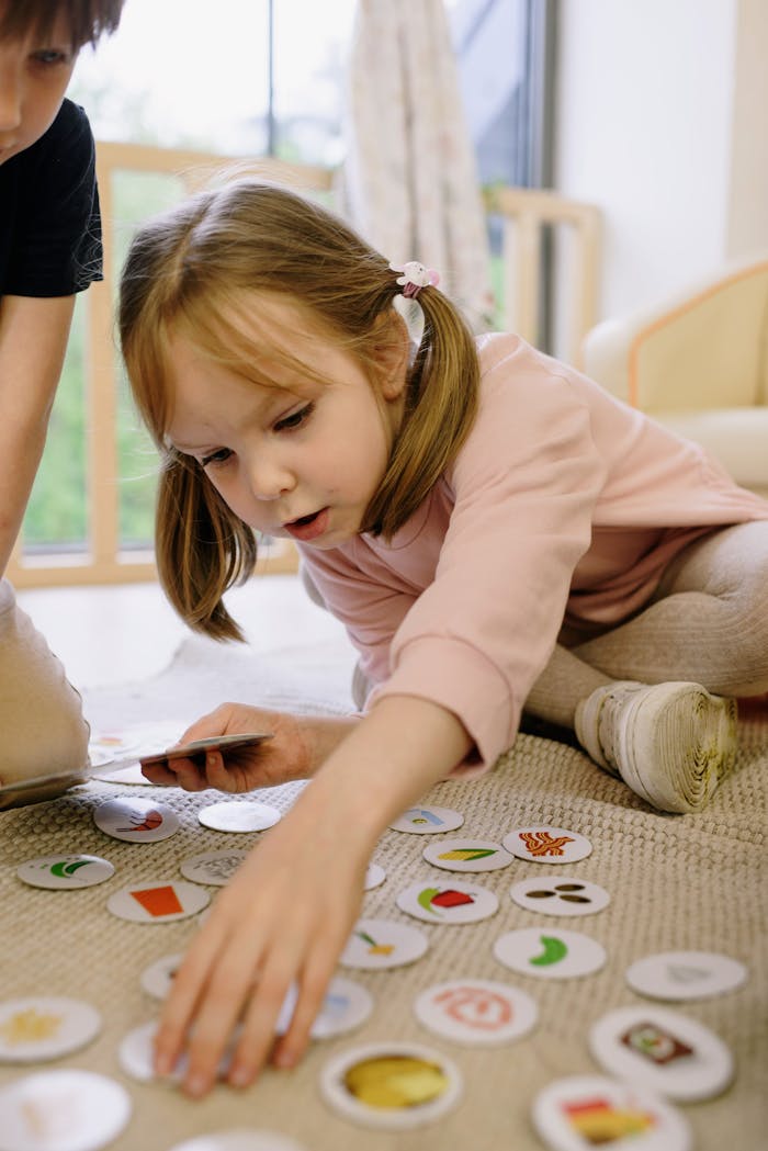 A young girl playing with educational cards on a rug, engaged in fun learning indoors.